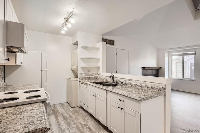 kitchen featuring kitchen peninsula, white dishwasher, sink, white cabinetry, and stacked washer and dryer