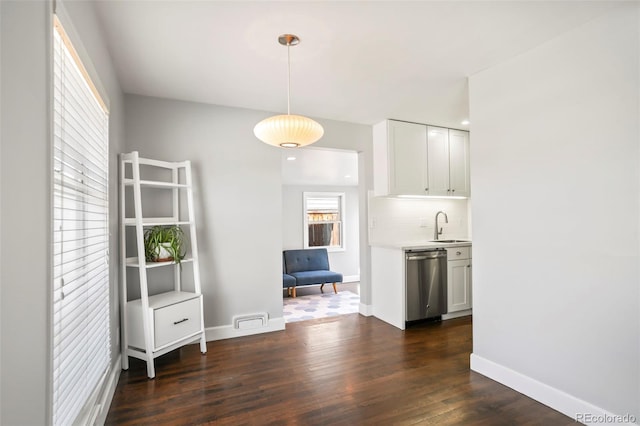 kitchen featuring a sink, backsplash, dark wood finished floors, light countertops, and dishwasher