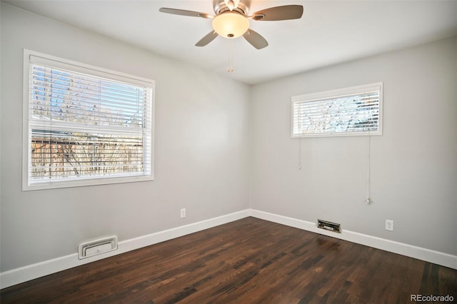 empty room with visible vents, dark wood-style floors, baseboards, and ceiling fan