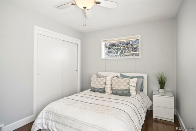 bedroom with a closet, dark wood finished floors, baseboards, and ceiling fan