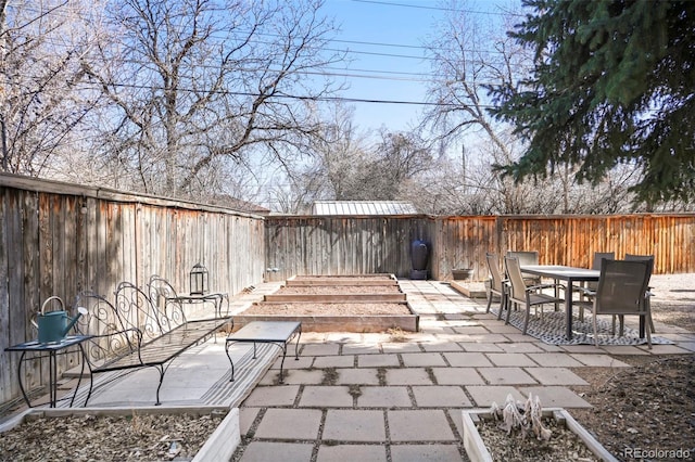 view of patio featuring outdoor dining area, a vegetable garden, and a fenced backyard