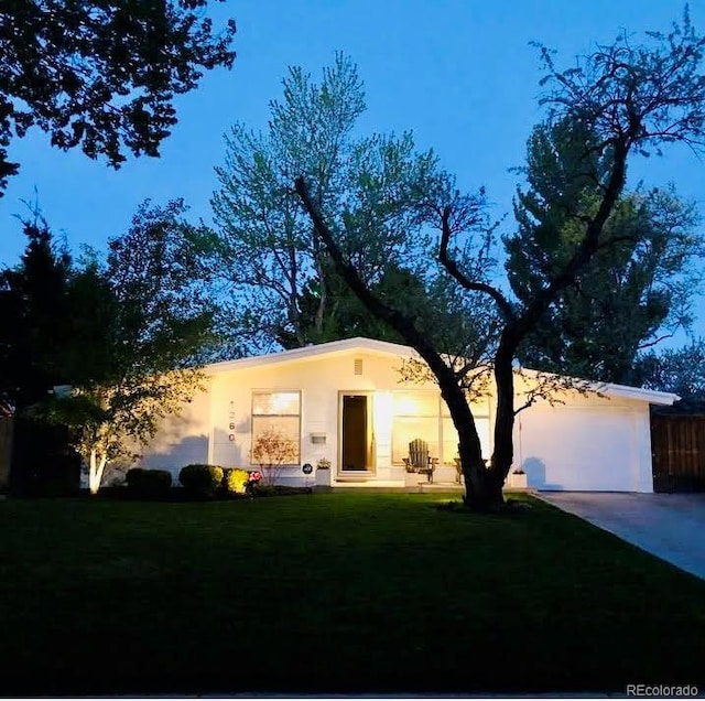 view of front of home featuring concrete driveway, an attached garage, a front lawn, and stucco siding