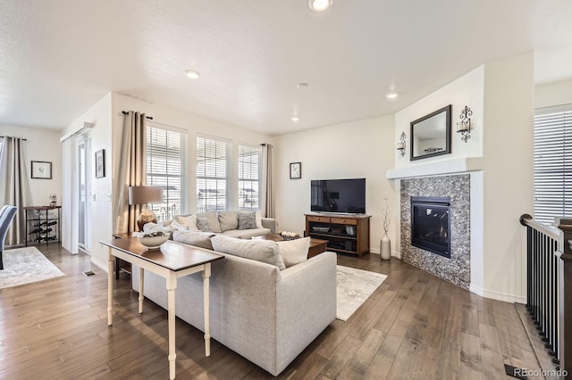 living room with a tiled fireplace, dark wood-type flooring, baseboards, and recessed lighting