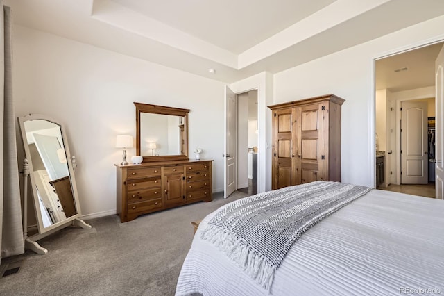 carpeted bedroom with a tray ceiling and baseboards