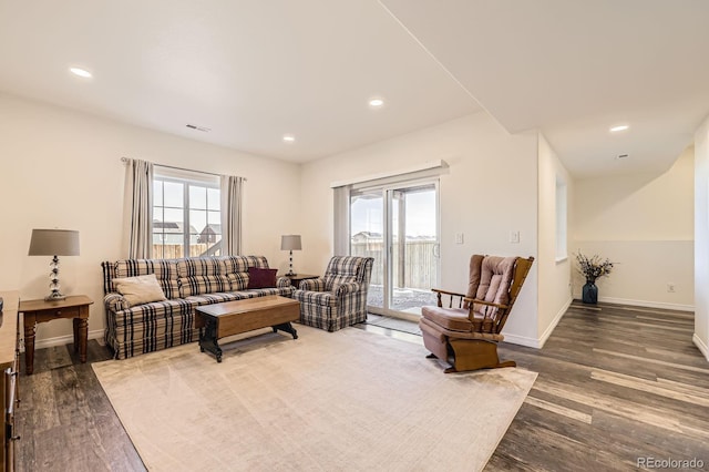 living area featuring a wealth of natural light, visible vents, and wood finished floors