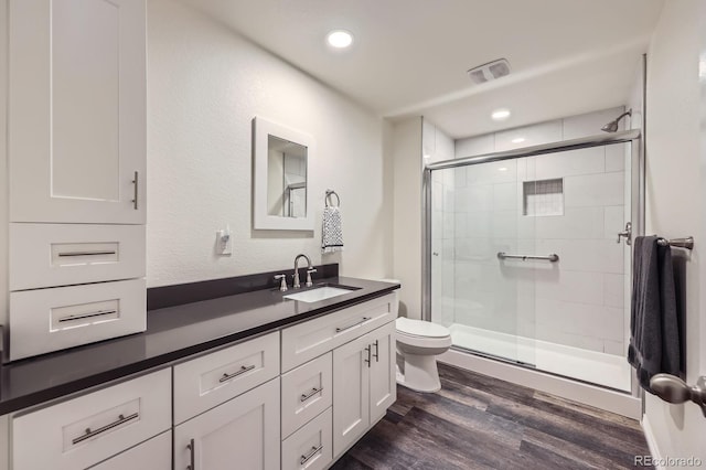 full bath featuring visible vents, a shower stall, wood finished floors, toilet, and vanity
