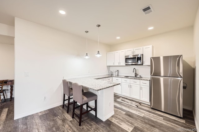 kitchen with visible vents, a peninsula, light stone countertops, stainless steel appliances, and a sink