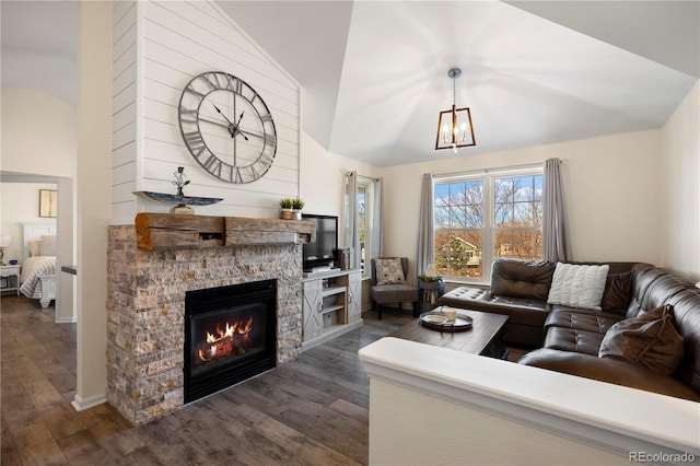 living room with dark wood-type flooring, a stone fireplace, an inviting chandelier, and lofted ceiling