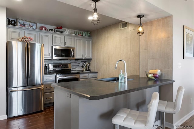 kitchen with sink, decorative light fixtures, kitchen peninsula, backsplash, and appliances with stainless steel finishes