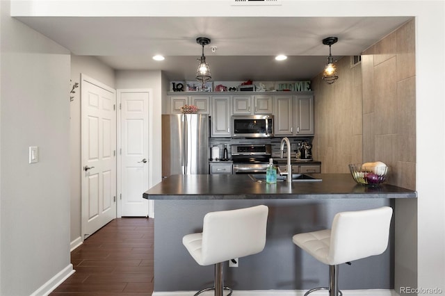 kitchen with pendant lighting, decorative backsplash, a kitchen bar, appliances with stainless steel finishes, and sink