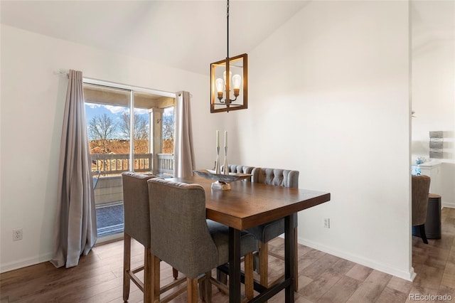 dining space with a notable chandelier, vaulted ceiling, and wood-type flooring