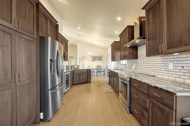 kitchen with wall chimney range hood, wine cooler, a chandelier, vaulted ceiling, and stainless steel appliances