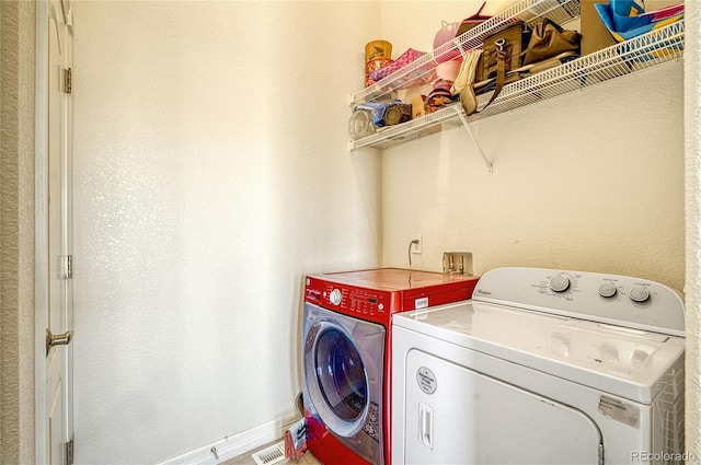 clothes washing area featuring washer and clothes dryer, laundry area, baseboards, and visible vents