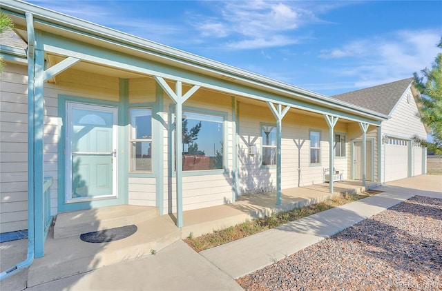 view of exterior entry with covered porch, concrete driveway, and an attached garage