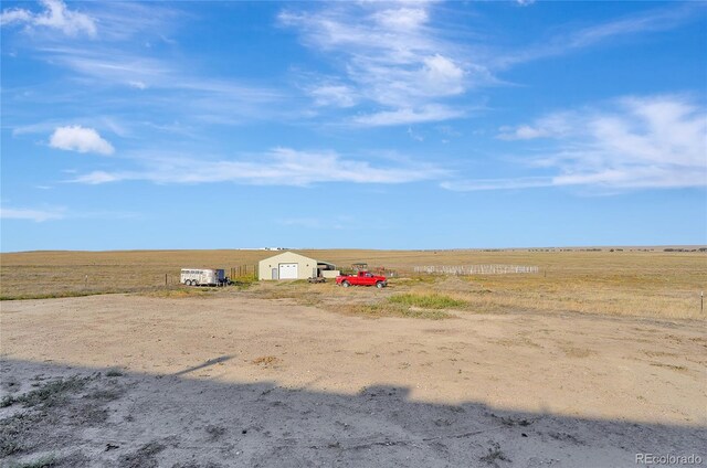 view of yard with an outdoor structure, a rural view, and a detached garage