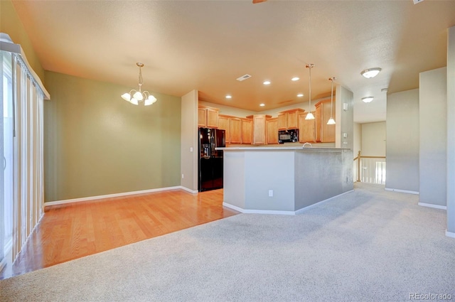 kitchen with black appliances, kitchen peninsula, hanging light fixtures, and light brown cabinets