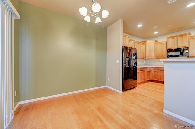 kitchen featuring pendant lighting, light hardwood / wood-style flooring, black appliances, and an inviting chandelier