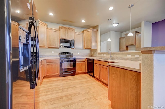 kitchen featuring decorative light fixtures, light hardwood / wood-style floors, sink, and black appliances