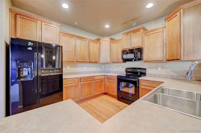 kitchen featuring sink, light hardwood / wood-style floors, and black appliances