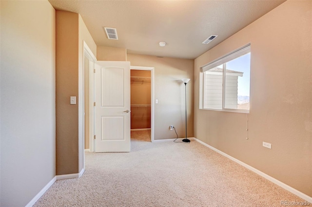 unfurnished bedroom featuring a walk in closet, light carpet, and a closet