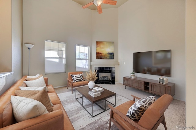 living room with a high ceiling, ceiling fan, light colored carpet, and a fireplace