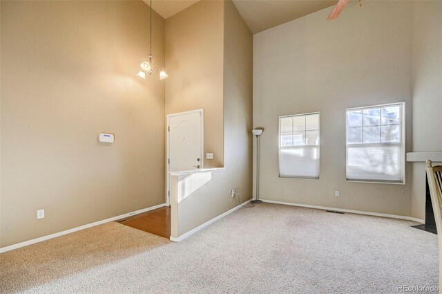 interior space with a towering ceiling, a chandelier, and carpet