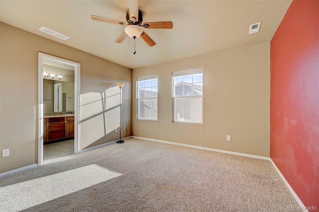 unfurnished bedroom featuring ceiling fan, light carpet, and ensuite bath