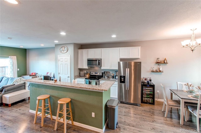 kitchen featuring white cabinetry, a breakfast bar area, stainless steel appliances, and a center island with sink