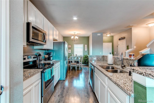 kitchen with light stone counters, appliances with stainless steel finishes, sink, and white cabinets