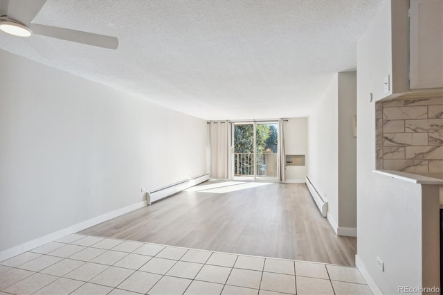 tiled spare room with ceiling fan, a baseboard radiator, and a textured ceiling