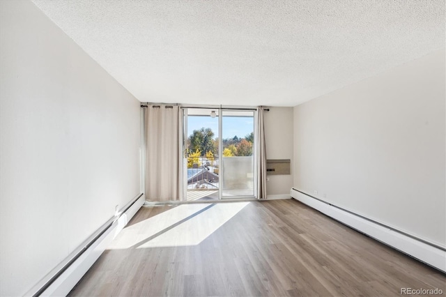 spare room featuring baseboard heating, expansive windows, and a textured ceiling