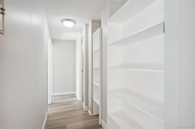 hallway featuring a textured ceiling and light hardwood / wood-style flooring