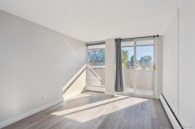 unfurnished room featuring a textured ceiling, light hardwood / wood-style floors, floor to ceiling windows, and a baseboard heating unit