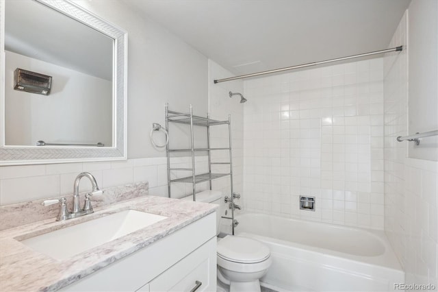 full bathroom with decorative backsplash, vanity, tiled shower / bath combo, tile walls, and toilet