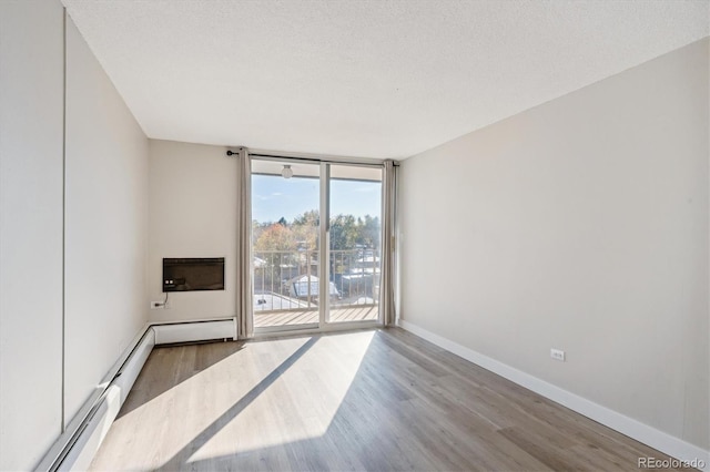 spare room with hardwood / wood-style floors, a textured ceiling, and a wall of windows