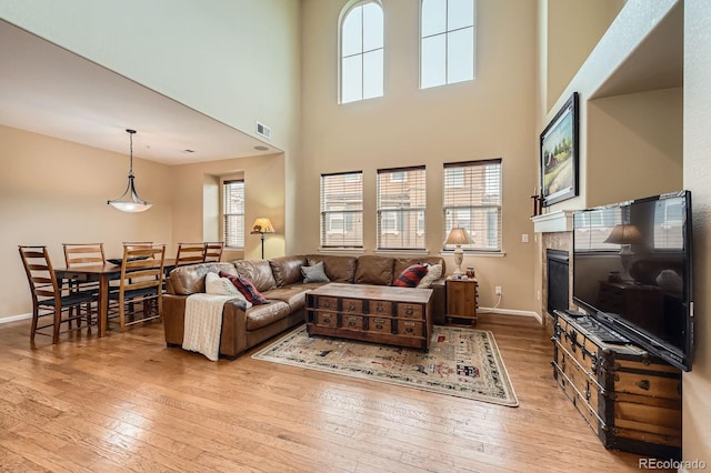living room featuring hardwood / wood-style flooring, healthy amount of natural light, a high ceiling, and baseboards