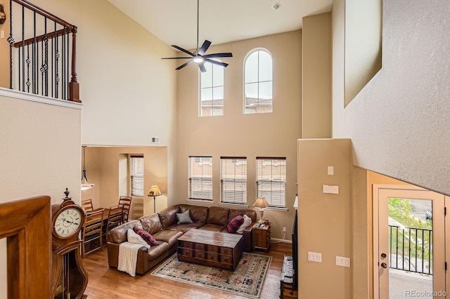 living area featuring a high ceiling, a ceiling fan, and wood finished floors