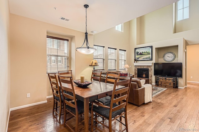 dining area with healthy amount of natural light, baseboards, a glass covered fireplace, and a high ceiling