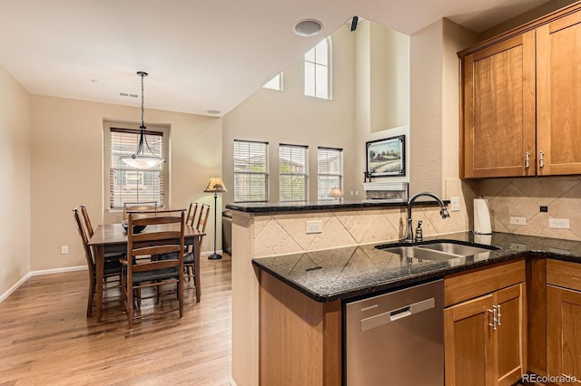kitchen featuring dishwasher, a sink, light wood-style floors, and brown cabinets