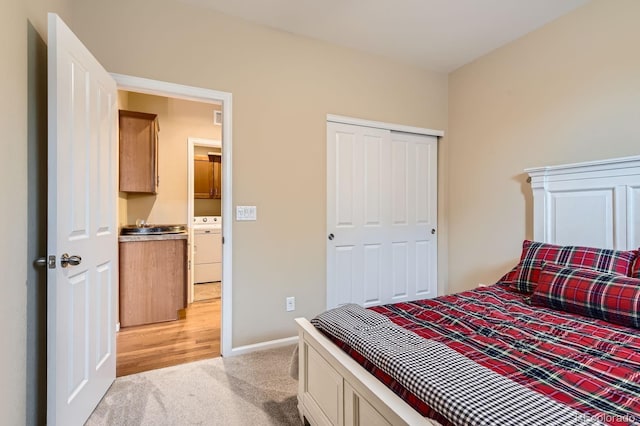 bedroom featuring light carpet, washer / clothes dryer, baseboards, and a closet