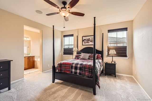 bedroom with light colored carpet, baseboards, ensuite bath, and a ceiling fan