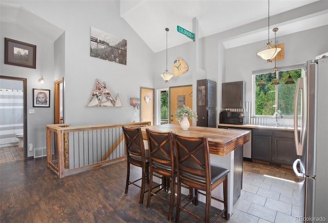 dining room with plenty of natural light, dark hardwood / wood-style floors, sink, and high vaulted ceiling