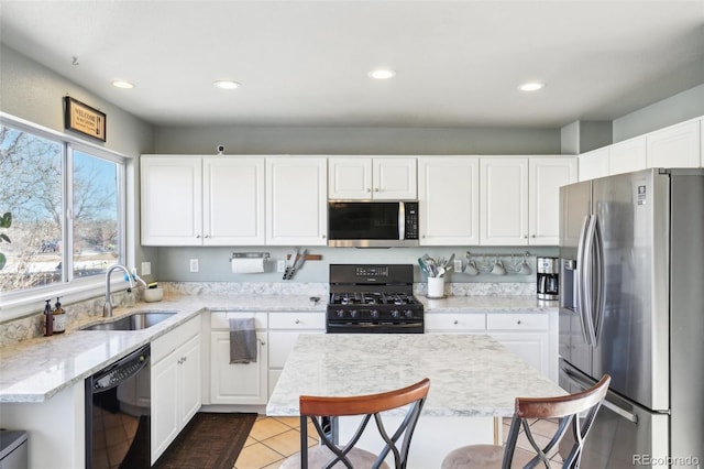 kitchen featuring black appliances, sink, white cabinetry, and a center island