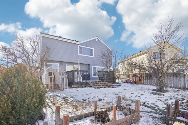 snow covered property with a wooden deck and a storage unit