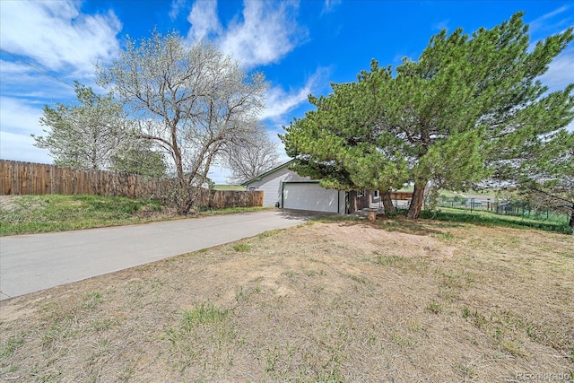 view of home's exterior featuring driveway, fence, and an attached garage