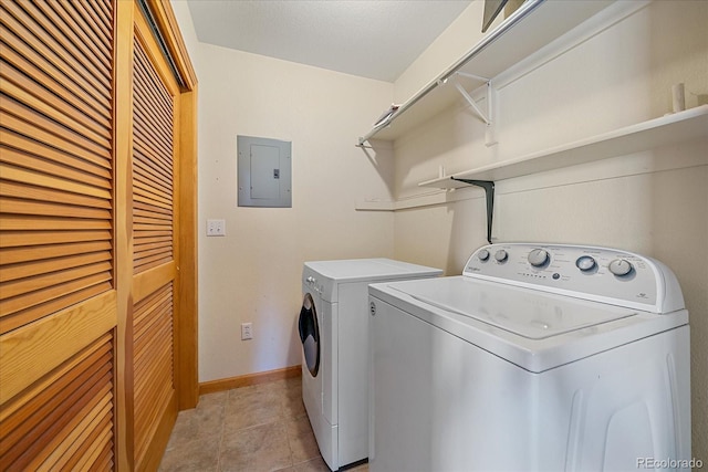 laundry area with electric panel, washer and clothes dryer, light tile patterned flooring, and baseboards