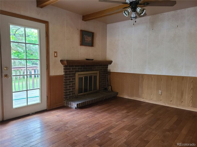 5274 W Rowland Pl, Littleton, CO 80128 - unfurnished living room with wood-type flooring, beam ceiling, a ceiling fan, wainscoting, and a fireplace
