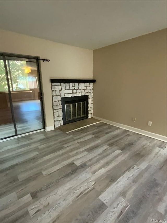 unfurnished living room with hardwood / wood-style floors and a stone fireplace