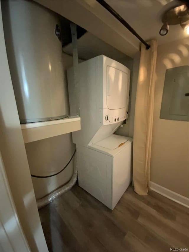 clothes washing area featuring stacked washer and dryer, electric panel, and hardwood / wood-style flooring