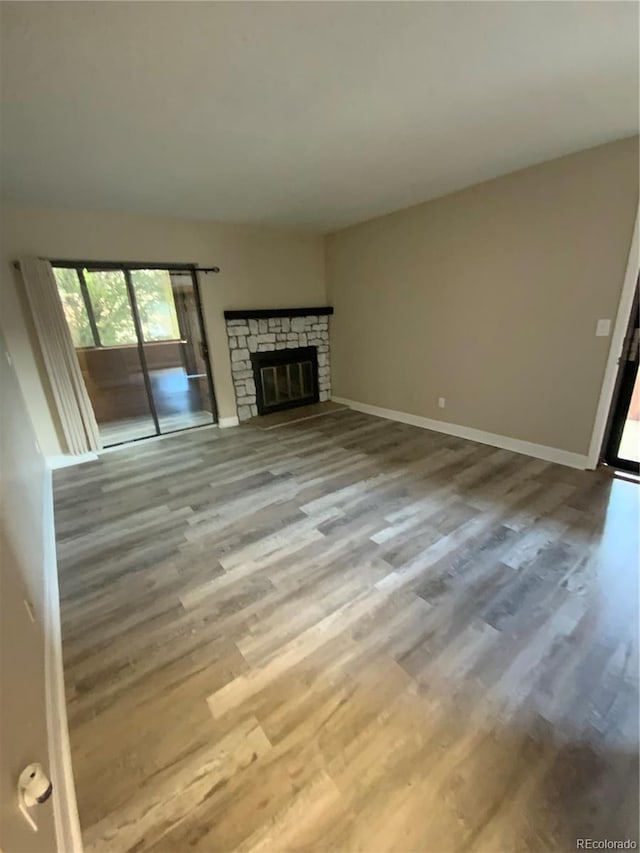 unfurnished living room featuring hardwood / wood-style floors and a stone fireplace